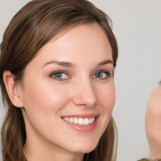 Joyful white young-adult female with medium  brown hair and grey eyes