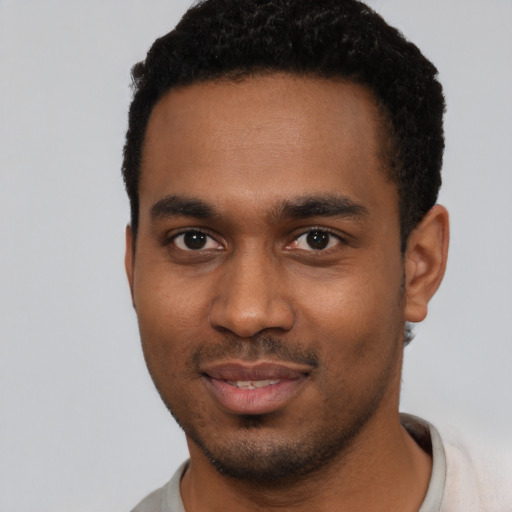 Joyful black young-adult male with short  black hair and brown eyes