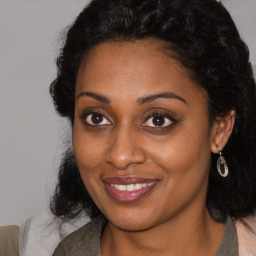 Joyful black young-adult female with long  brown hair and brown eyes