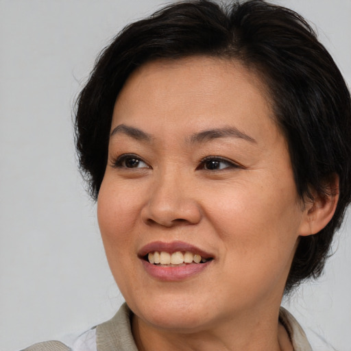 Joyful asian adult female with medium  brown hair and brown eyes