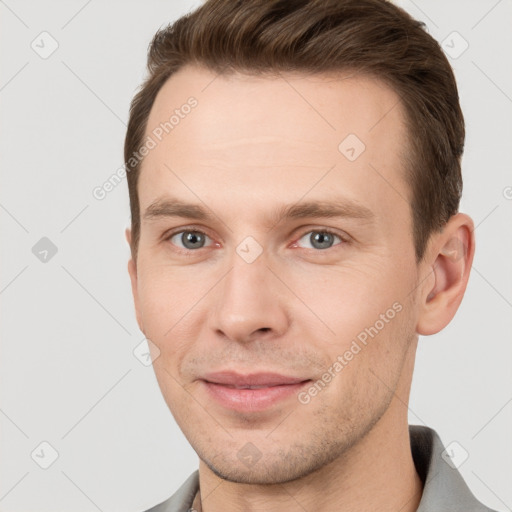 Joyful white young-adult male with short  brown hair and grey eyes