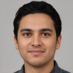 Joyful latino young-adult male with short  black hair and brown eyes