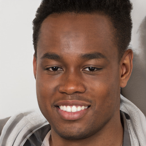 Joyful black young-adult male with short  brown hair and brown eyes