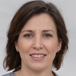 Joyful white adult female with medium  brown hair and grey eyes