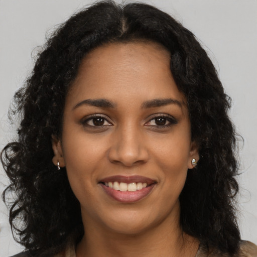 Joyful black young-adult female with long  brown hair and brown eyes