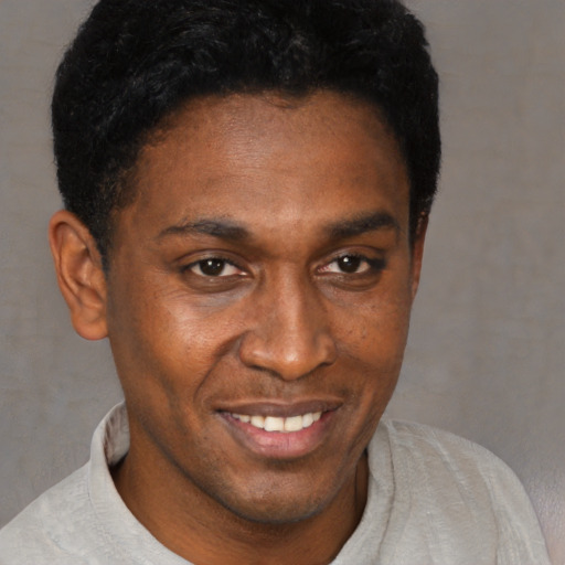Joyful black adult male with short  black hair and brown eyes