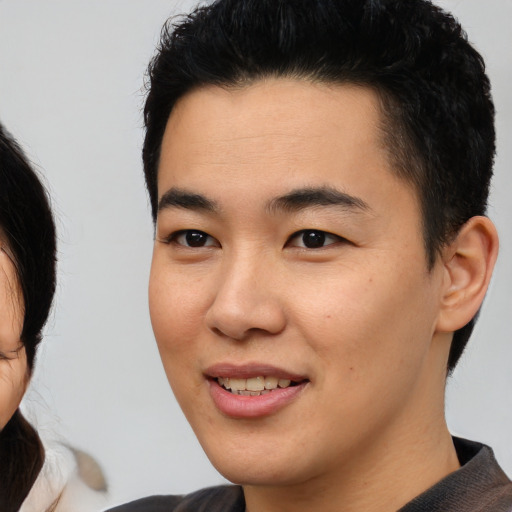 Joyful asian young-adult male with short  brown hair and brown eyes