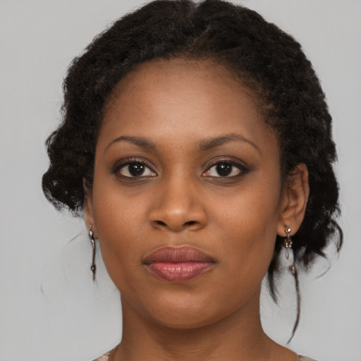 Joyful black young-adult female with long  brown hair and brown eyes