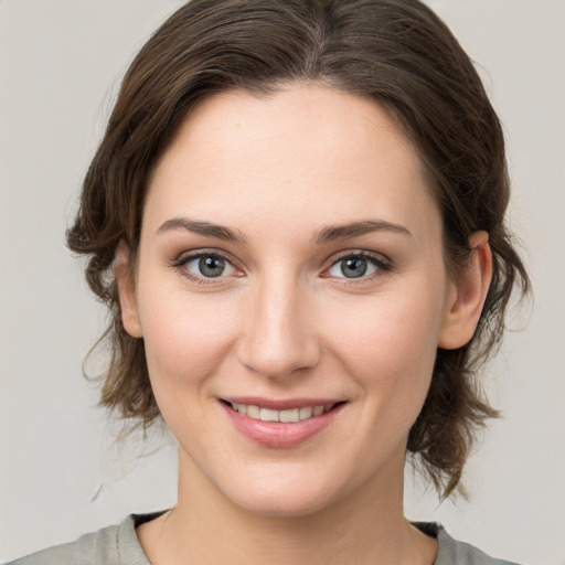 Joyful white young-adult female with medium  brown hair and grey eyes