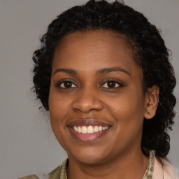 Joyful black young-adult female with long  brown hair and brown eyes