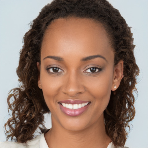 Joyful black young-adult female with long  brown hair and brown eyes