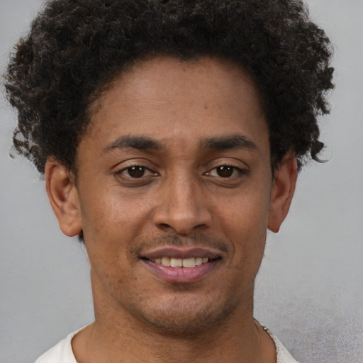 Joyful black young-adult male with short  brown hair and brown eyes