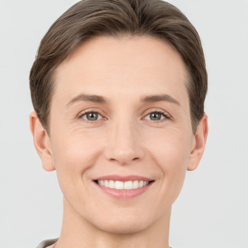 Joyful white young-adult female with short  brown hair and grey eyes