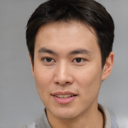 Joyful asian young-adult male with short  brown hair and brown eyes