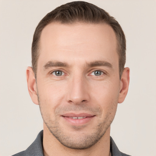 Joyful white young-adult male with short  brown hair and grey eyes