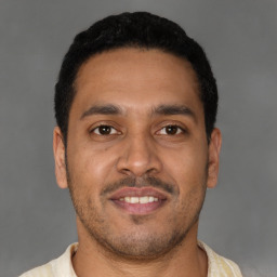 Joyful latino young-adult male with short  brown hair and brown eyes