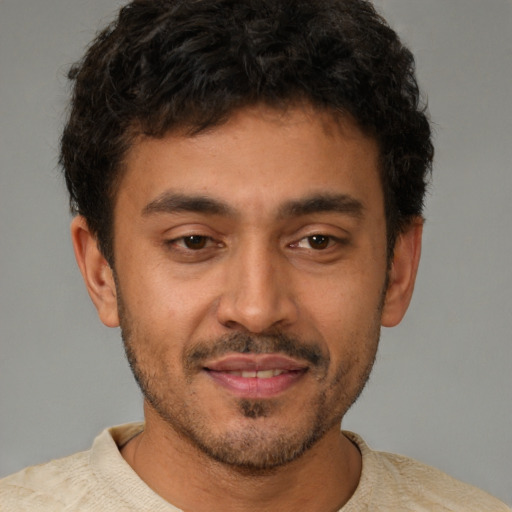 Joyful latino young-adult male with short  brown hair and brown eyes