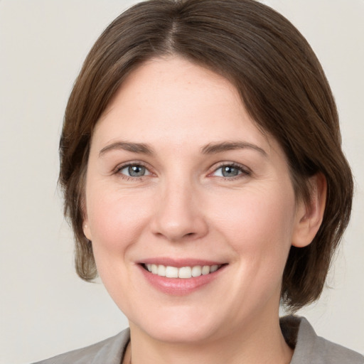 Joyful white young-adult female with medium  brown hair and grey eyes