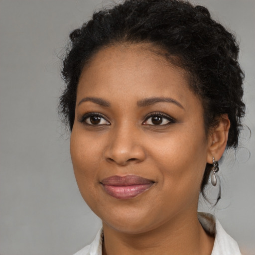 Joyful black young-adult female with long  brown hair and brown eyes