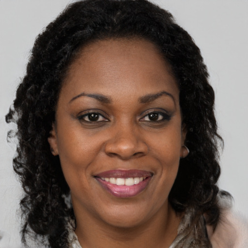 Joyful black young-adult female with long  brown hair and brown eyes