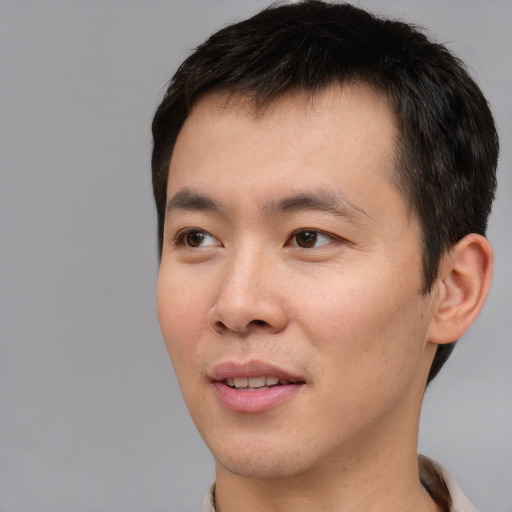 Joyful asian young-adult male with short  brown hair and brown eyes