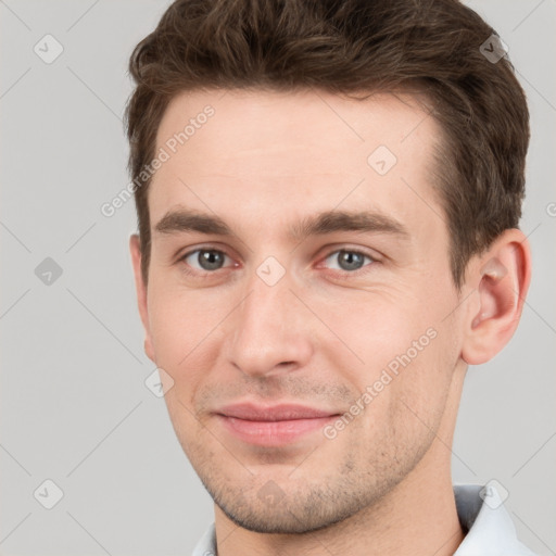 Joyful white young-adult male with short  brown hair and grey eyes