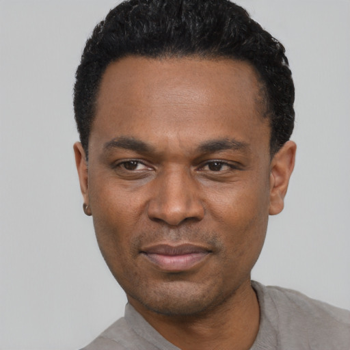 Joyful black young-adult male with short  black hair and brown eyes