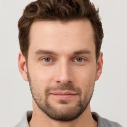 Joyful white young-adult male with short  brown hair and grey eyes