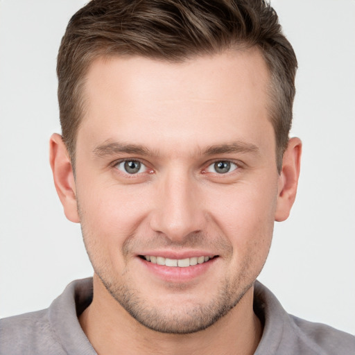 Joyful white young-adult male with short  brown hair and grey eyes