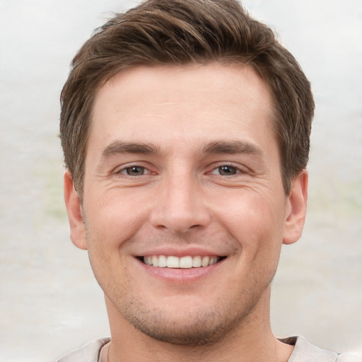 Joyful white young-adult male with short  brown hair and grey eyes