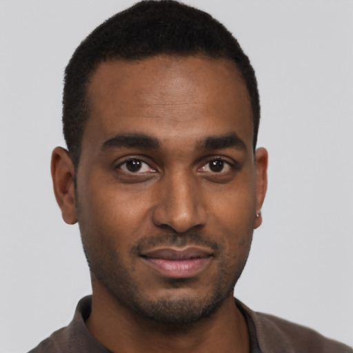 Joyful black young-adult male with short  brown hair and brown eyes