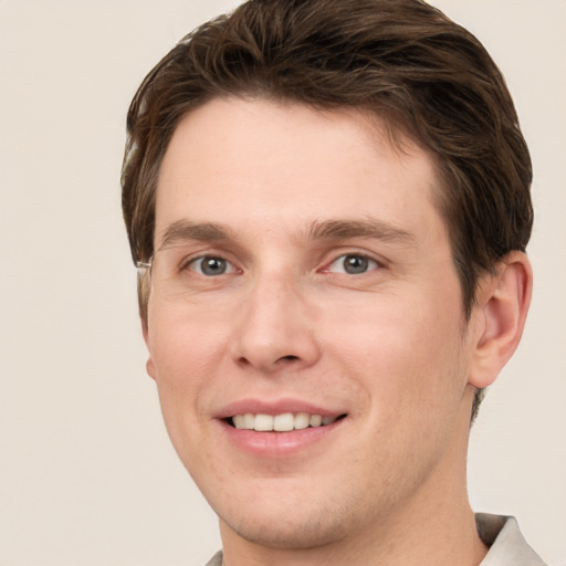 Joyful white young-adult male with short  brown hair and grey eyes