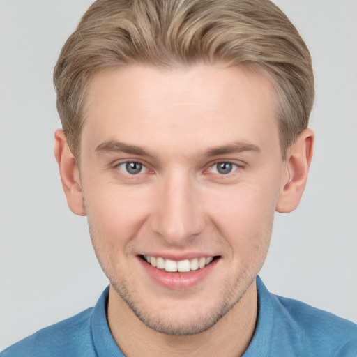 Joyful white young-adult male with short  brown hair and grey eyes