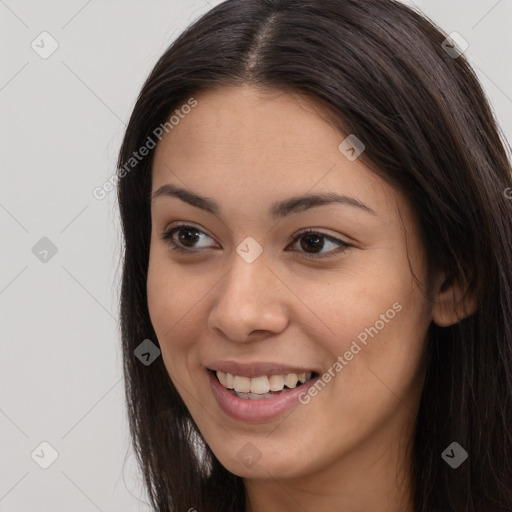 Joyful black young-adult female with long  brown hair and brown eyes