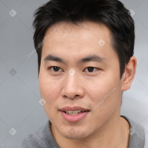 Joyful asian young-adult male with short  brown hair and brown eyes