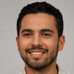 Joyful white young-adult male with short  black hair and brown eyes