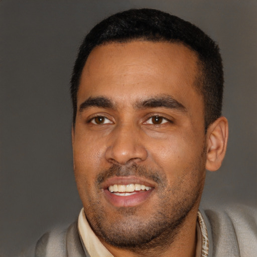 Joyful black young-adult male with short  black hair and brown eyes