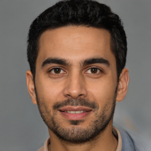 Joyful latino young-adult male with short  black hair and brown eyes