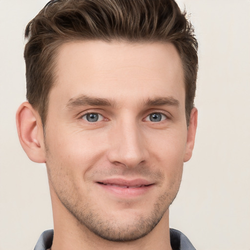 Joyful white young-adult male with short  brown hair and grey eyes