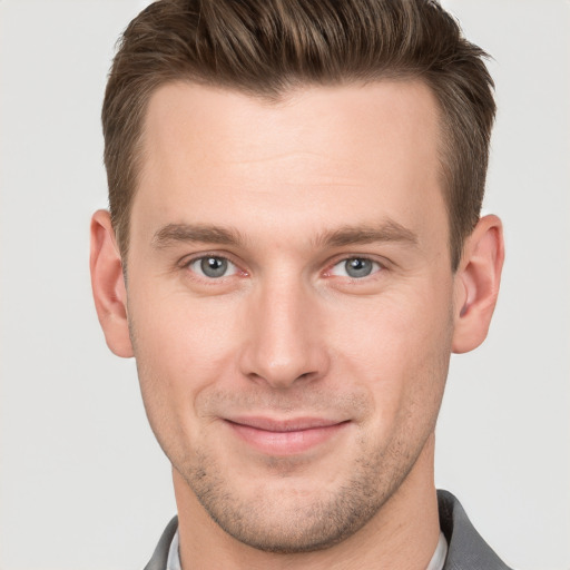 Joyful white young-adult male with short  brown hair and grey eyes