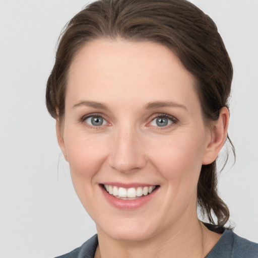 Joyful white young-adult female with medium  brown hair and grey eyes