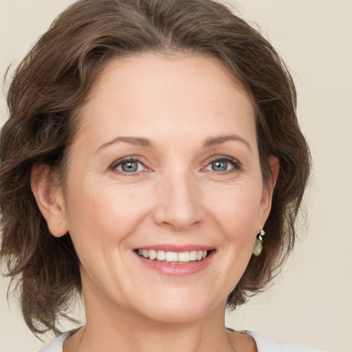 Joyful white adult female with medium  brown hair and green eyes