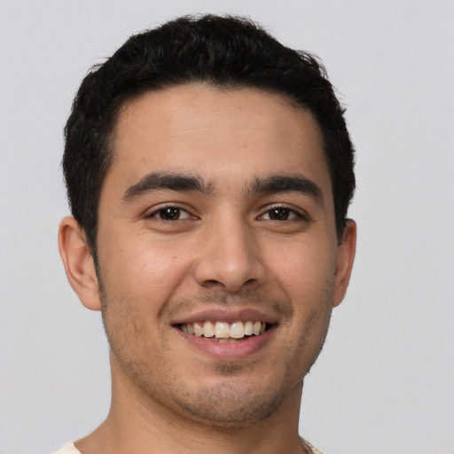 Joyful latino young-adult male with short  brown hair and brown eyes