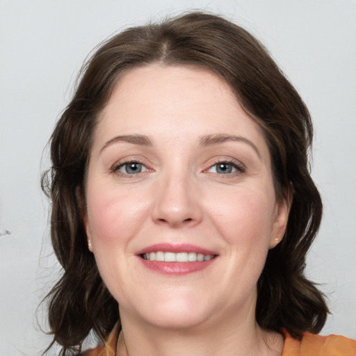 Joyful white young-adult female with medium  brown hair and grey eyes