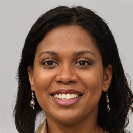 Joyful black young-adult female with long  brown hair and brown eyes