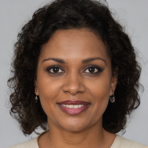 Joyful black young-adult female with long  brown hair and brown eyes