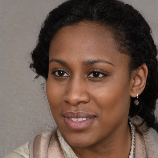 Joyful black young-adult female with long  black hair and brown eyes