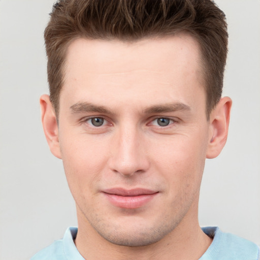 Joyful white young-adult male with short  brown hair and grey eyes