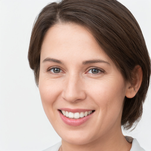 Joyful white young-adult female with medium  brown hair and grey eyes