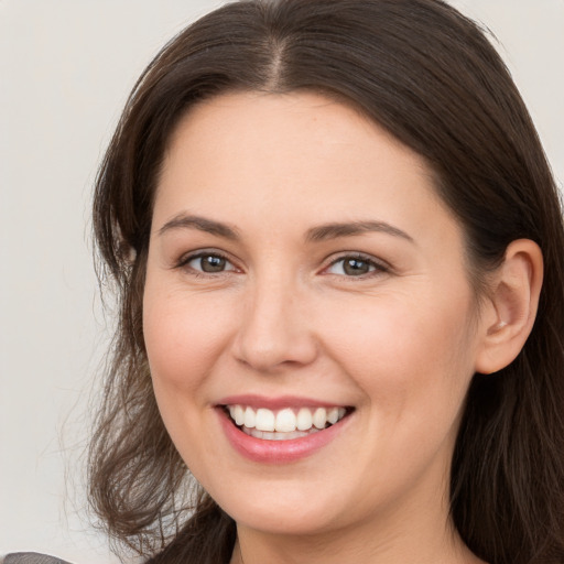 Joyful white young-adult female with long  brown hair and brown eyes